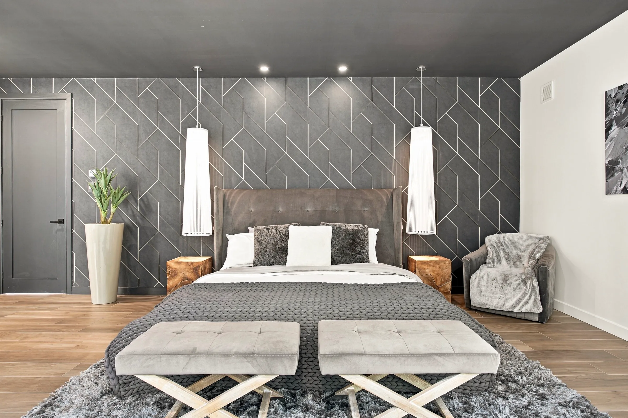 Chambre au mur de tête en losanges gris, literie claire et suspensions de part et d’autre du lit