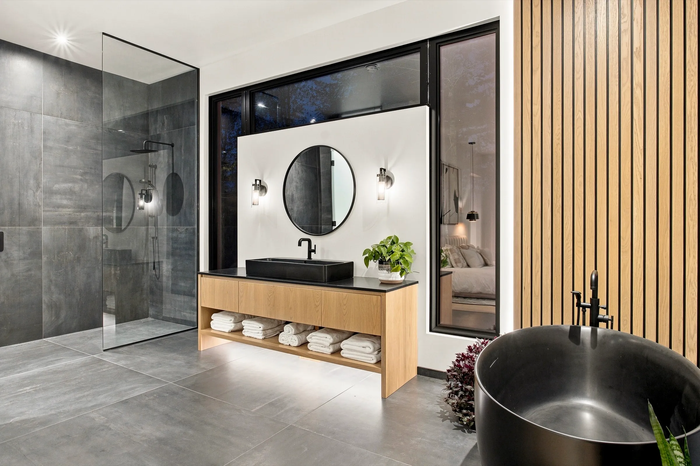 Salle de bain contemporaine, vasque et baignoire noires, lambris de bois vertical et douche vitrée