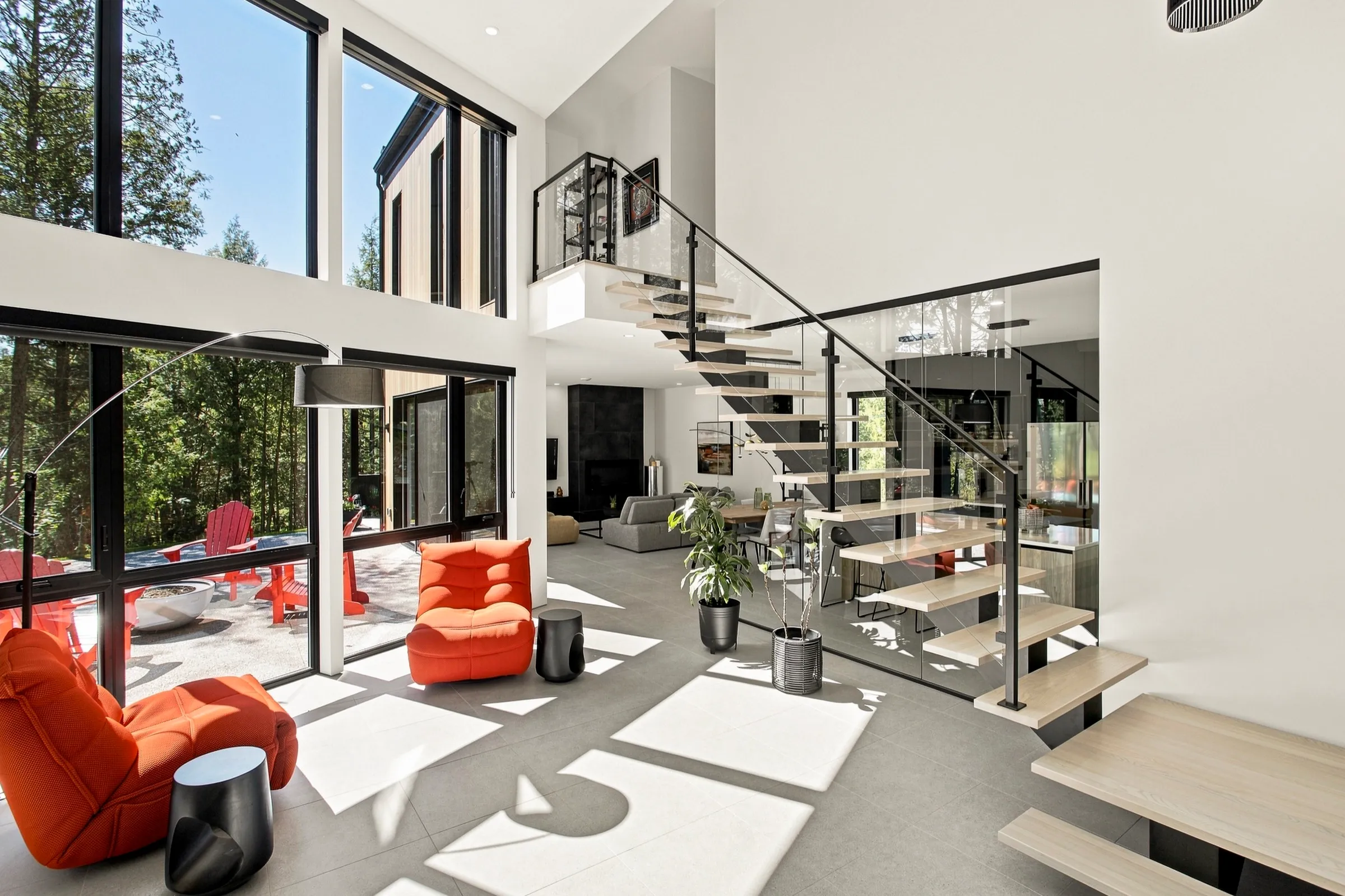 Vaste volume vitré traversé de lumière, escalier blanc suspendu et fauteuils rouges
